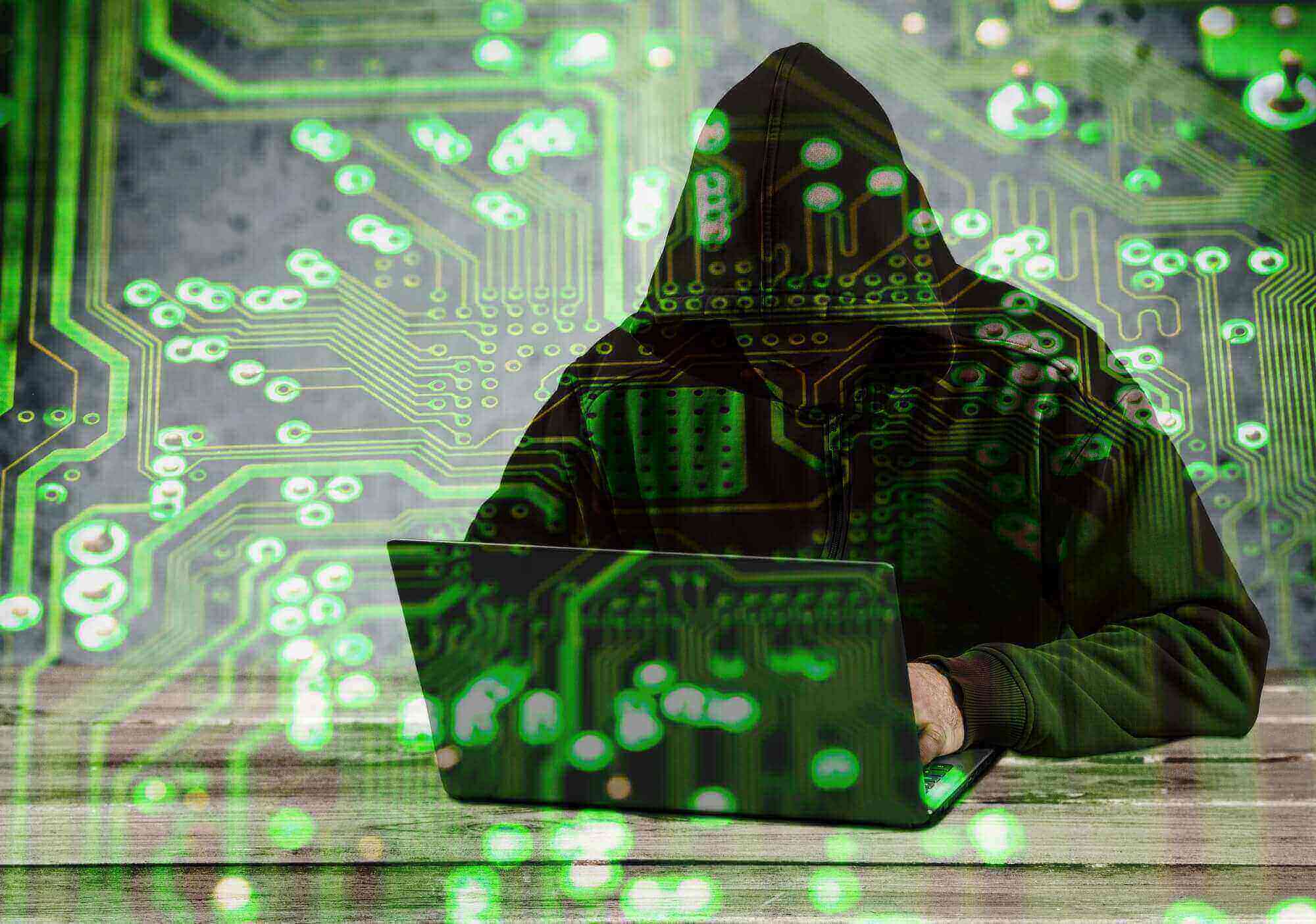 man in hoodie hacking on his laptop