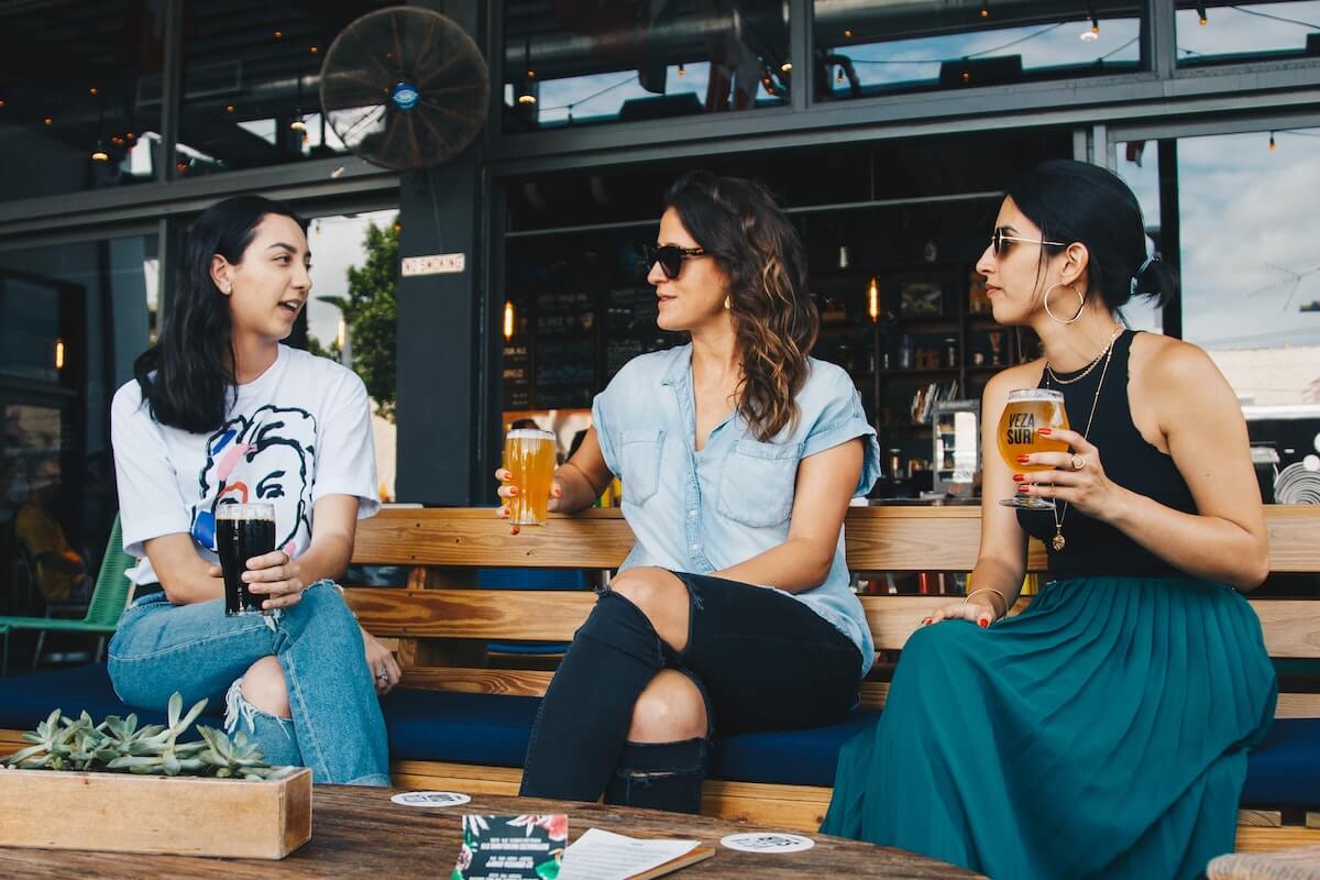 three women drinking beer an an outdoor table at bar/restaurant
