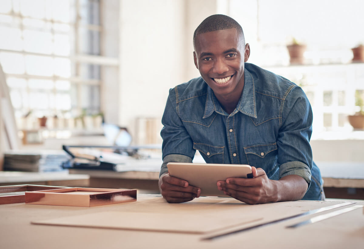 man smiling at camera while using tablet